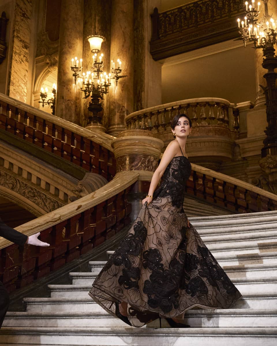 A woman in ballgown ascends grand staircase of opera