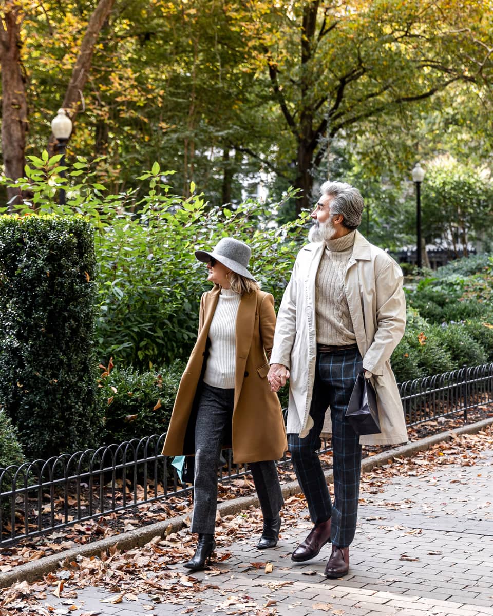 A man and woman walking next to a park.