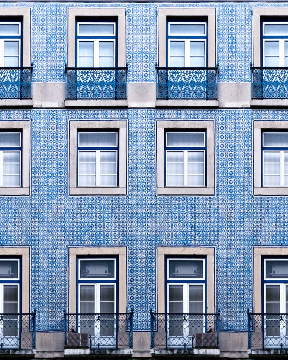 A blue tiled wall with many windows and balconies.