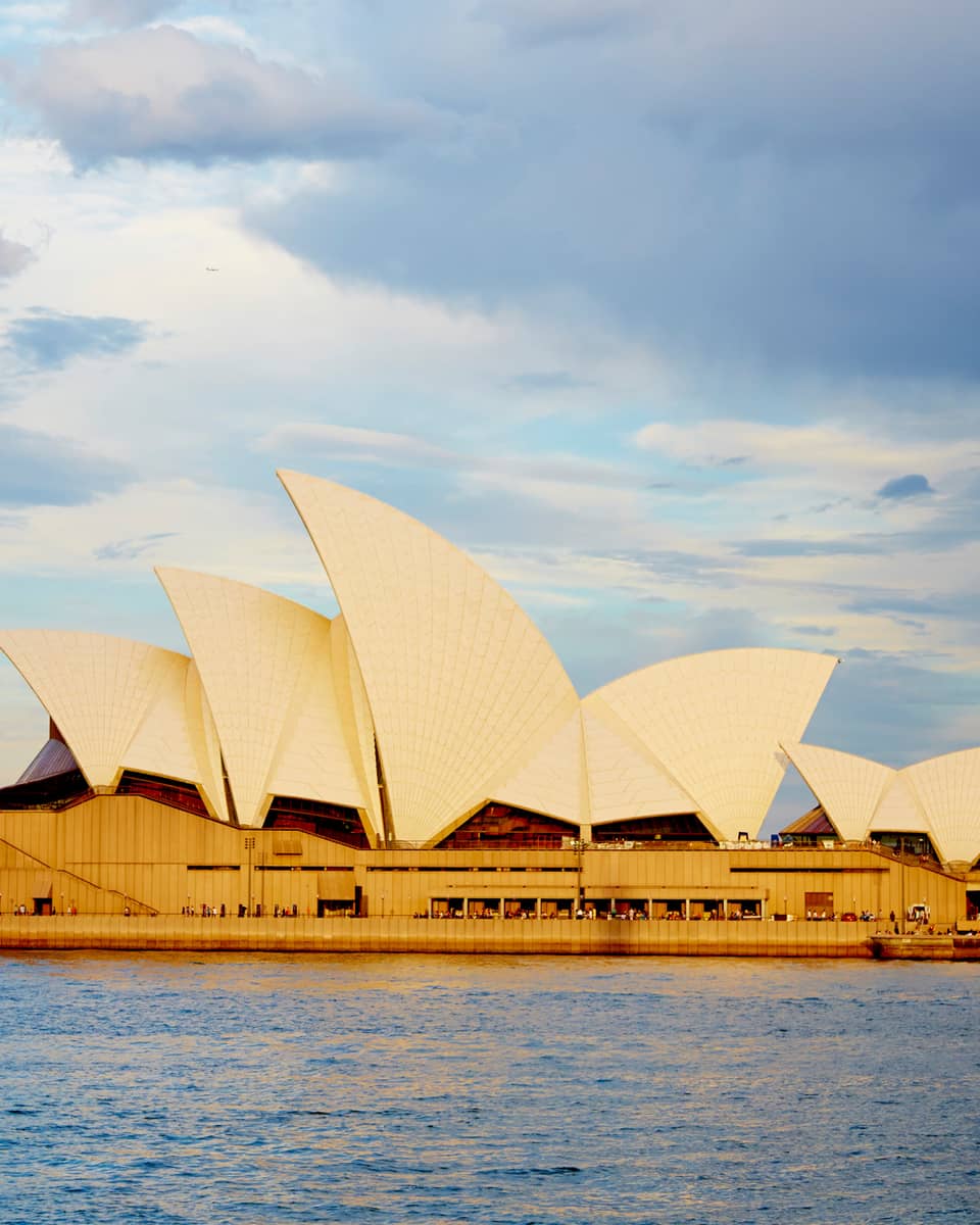 View of Sydney Opera House with its white, sailboat-like roof from harbour