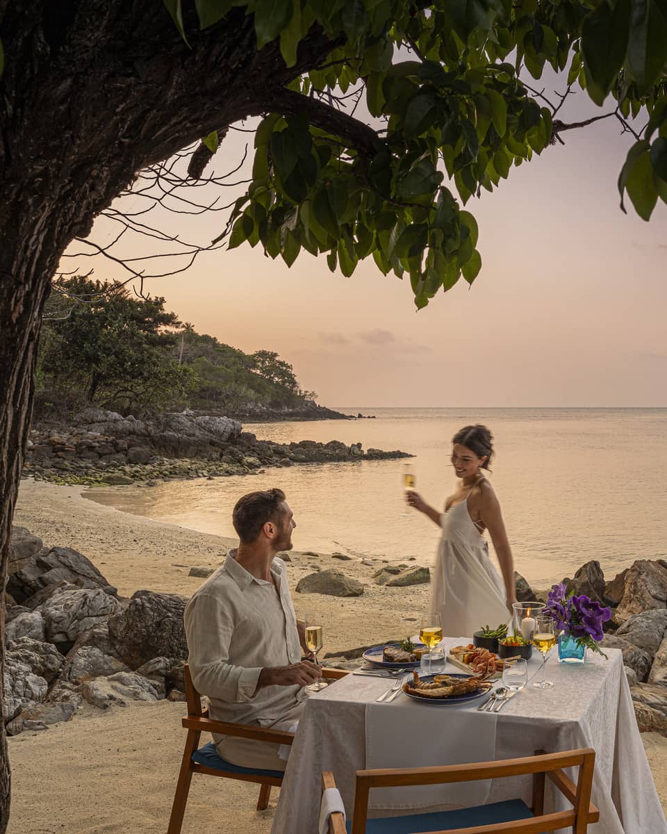 A beach dinner date at dusk, with a couple enjoying a serene seaside view.