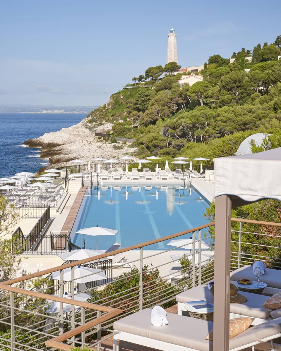 View from terrace of Club Dauphin pool, Mediterranean, green hillside and lighthouse