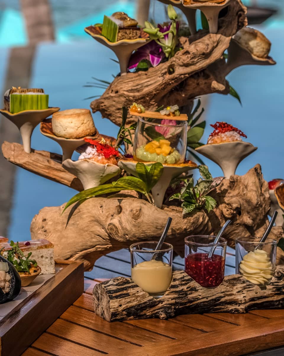 Afternoon tea spread with sweets and savouries presented on a piece of driftwood