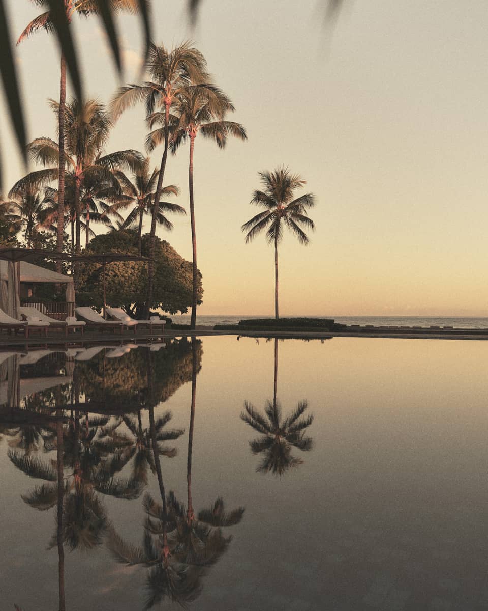 A reflective pool at a tropical resort with beach in the distance
