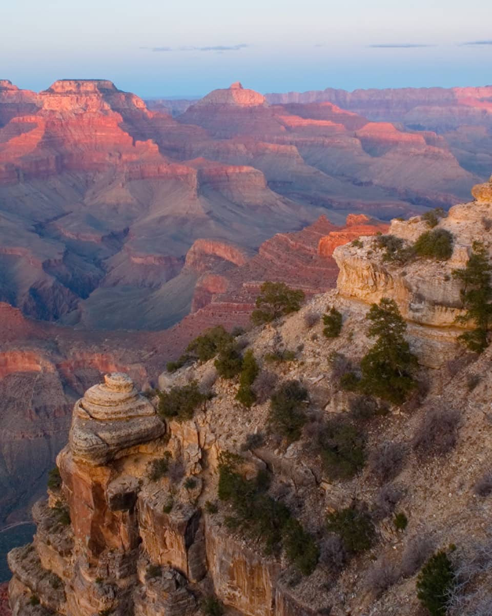 Sweeping view of Grand Canyon cliffs, canyon ridges, pink light from sunset