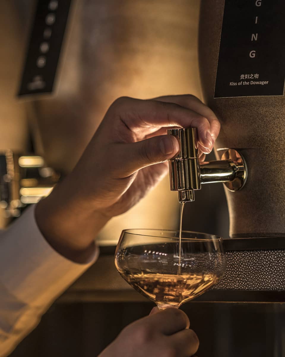 Close-up of bartender pouring liquor from tap into cocktail glass