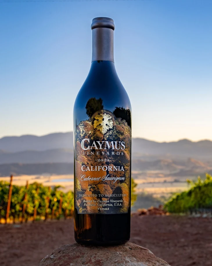 A bottle of Caymus California Cabernet Sauvignon overlooking the vineyards