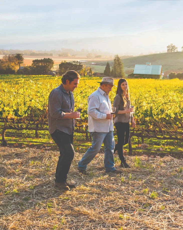 The Wagner family walking through a sunlit Caymus vineyard