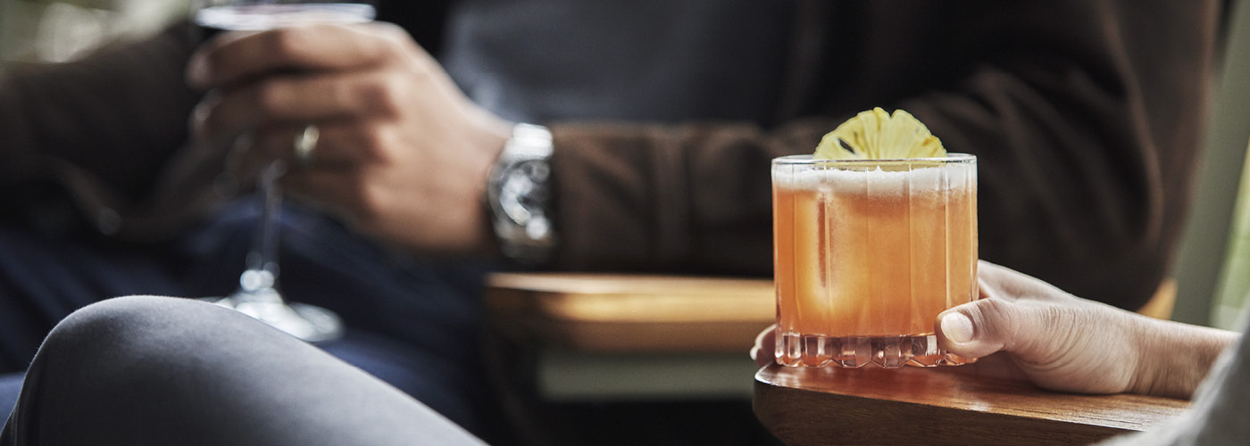 Close up of a woman holding a cocktail garnishes with pineapple