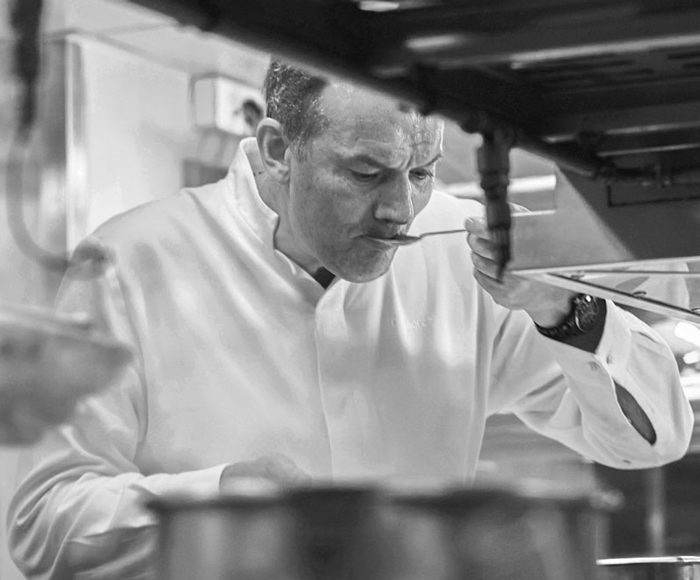 Chef Lesquer tests a dish in his kitchen