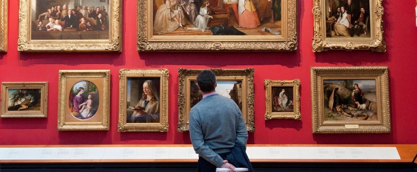 Man looks at paintings in the Victoria and Albert Museum, London, England, UK.