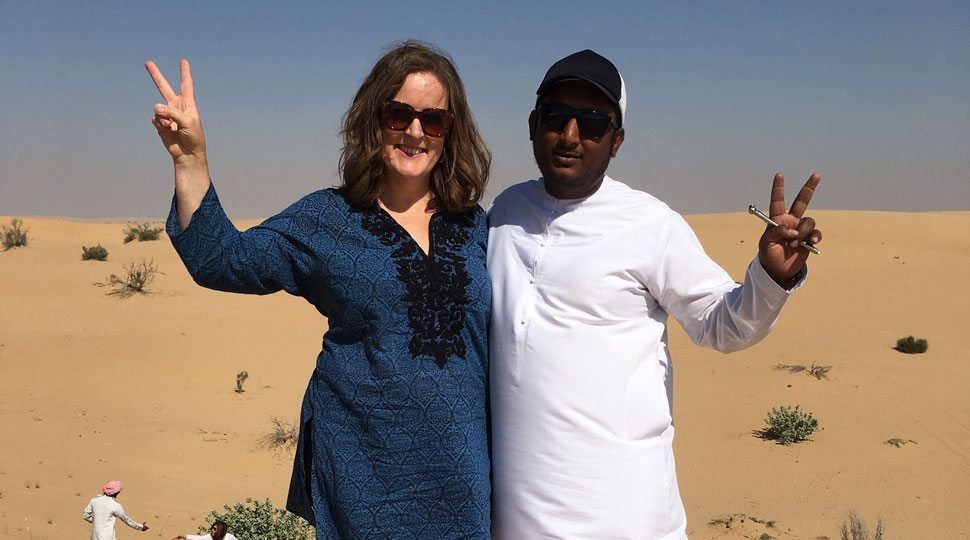 A man and a woman hold peace signs and smile at the camera