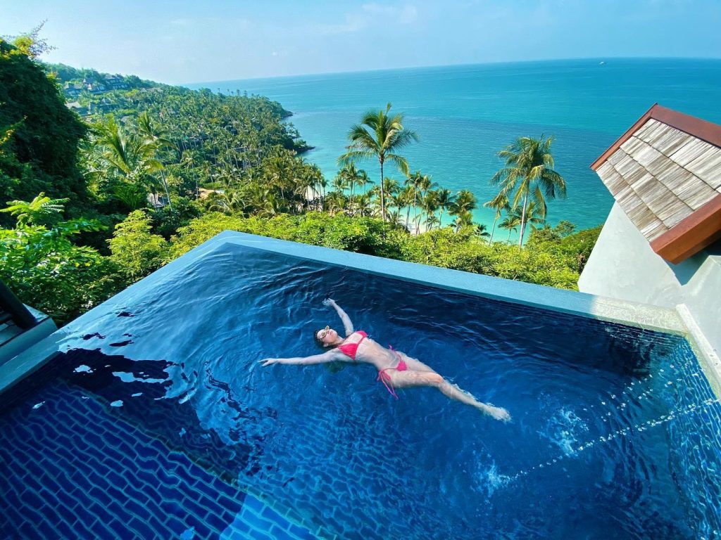 Woman in red bikini back floats in an infinity pool