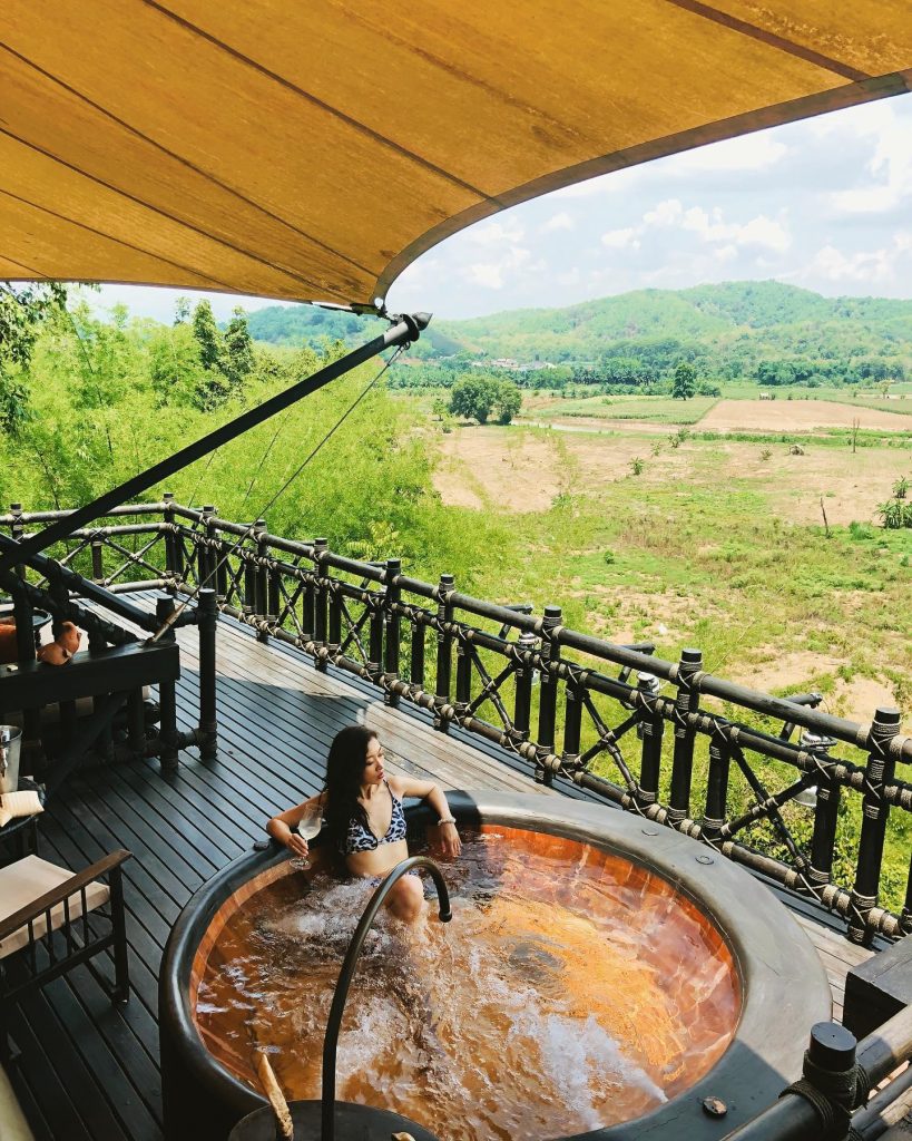A woman in a bathing suit lounges in a hot tub on a deck