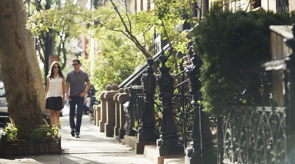 man and woman with sunglasses holding hands on sidewalk, West Village