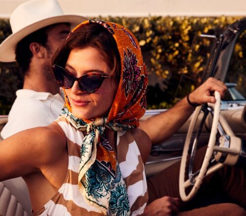 A woman in a scarf and a man in a hat in an old vintage car