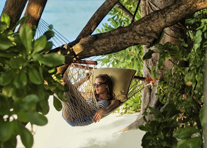 Woman lounges in a beachside hammock