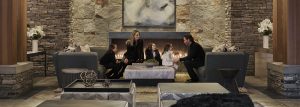 A family sits in a living room with a fireplace in the background