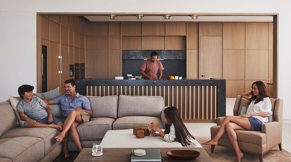 A family sits in a living room while a personal chef prepares a meal