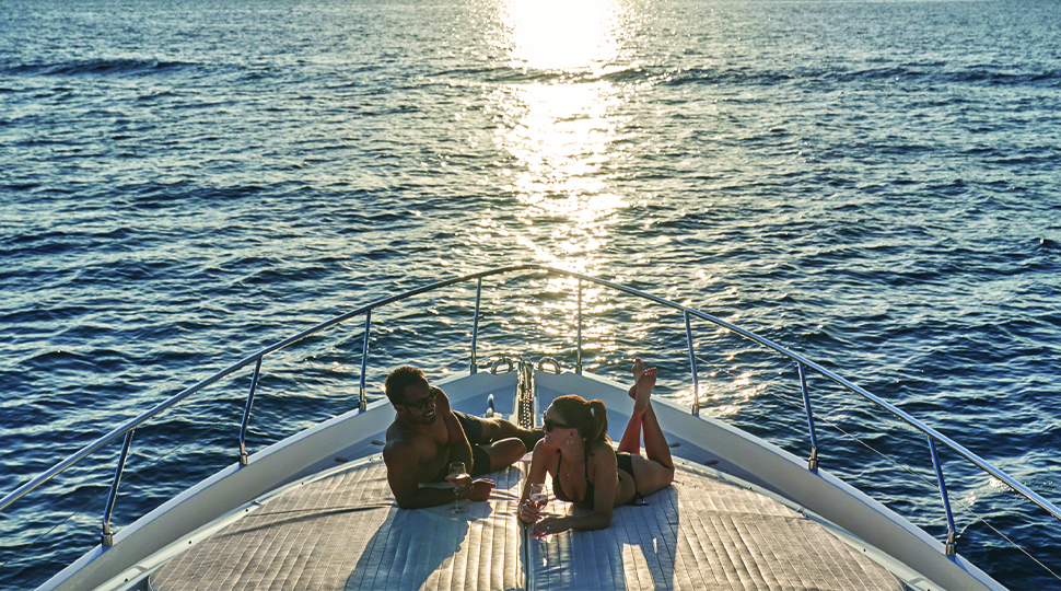 Two people lay on the bow of a yacht