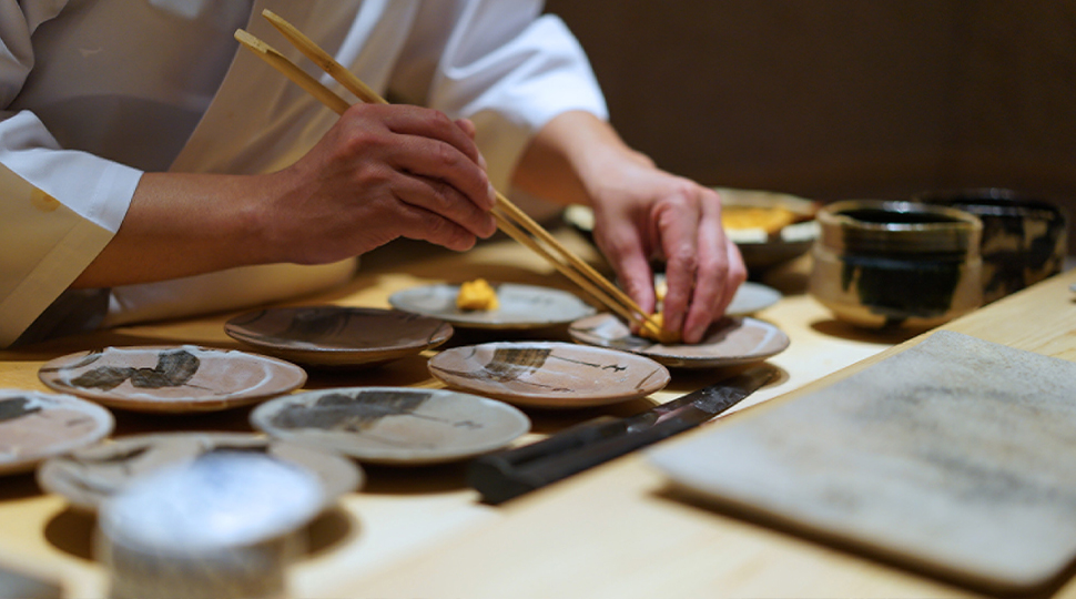 Close up of chef's hand placing sushi on small round plates at Sushi Saito in Hong Kong