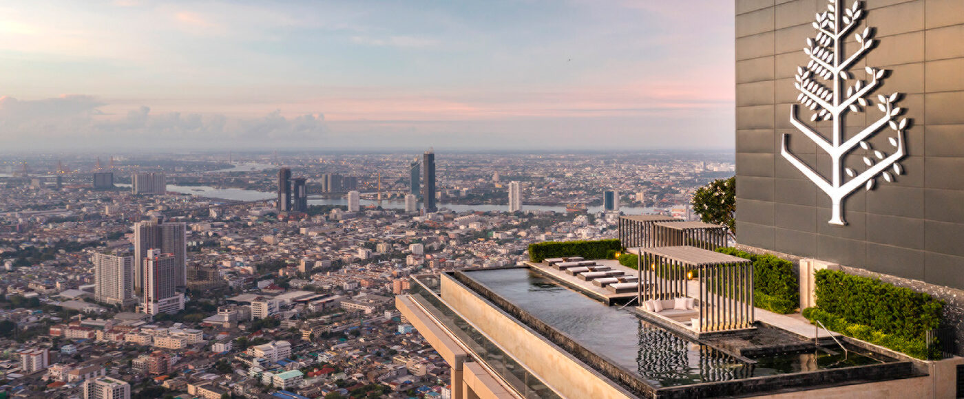 Rooftop pool sits on top of a skyscraper overlooking the city with a large Four Seasons tree logo next to it