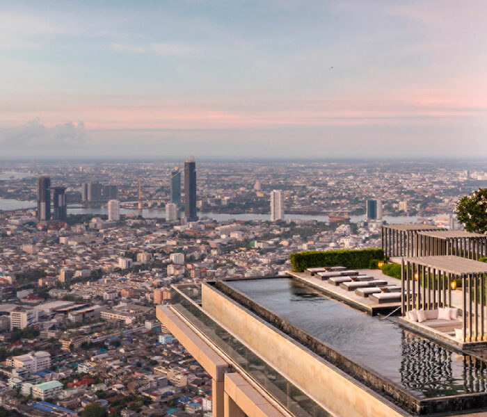 Rooftop pool sits on top of a skyscraper overlooking the city with a large Four Seasons tree logo next to it