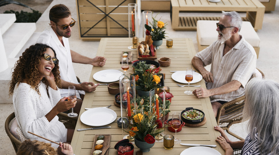 A family of four sits laughing together around a dinner table