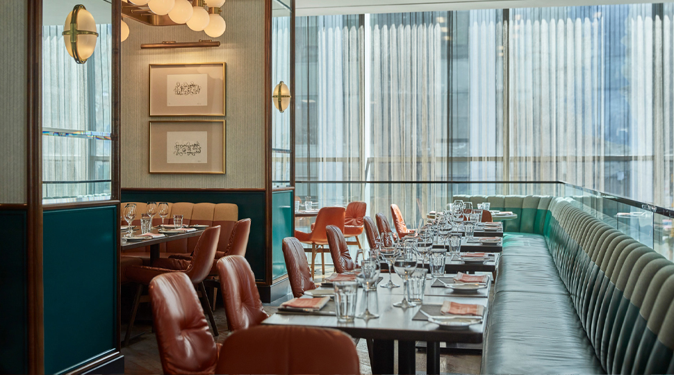Interior of restaurant with teal leather banquette and brown leather chairs