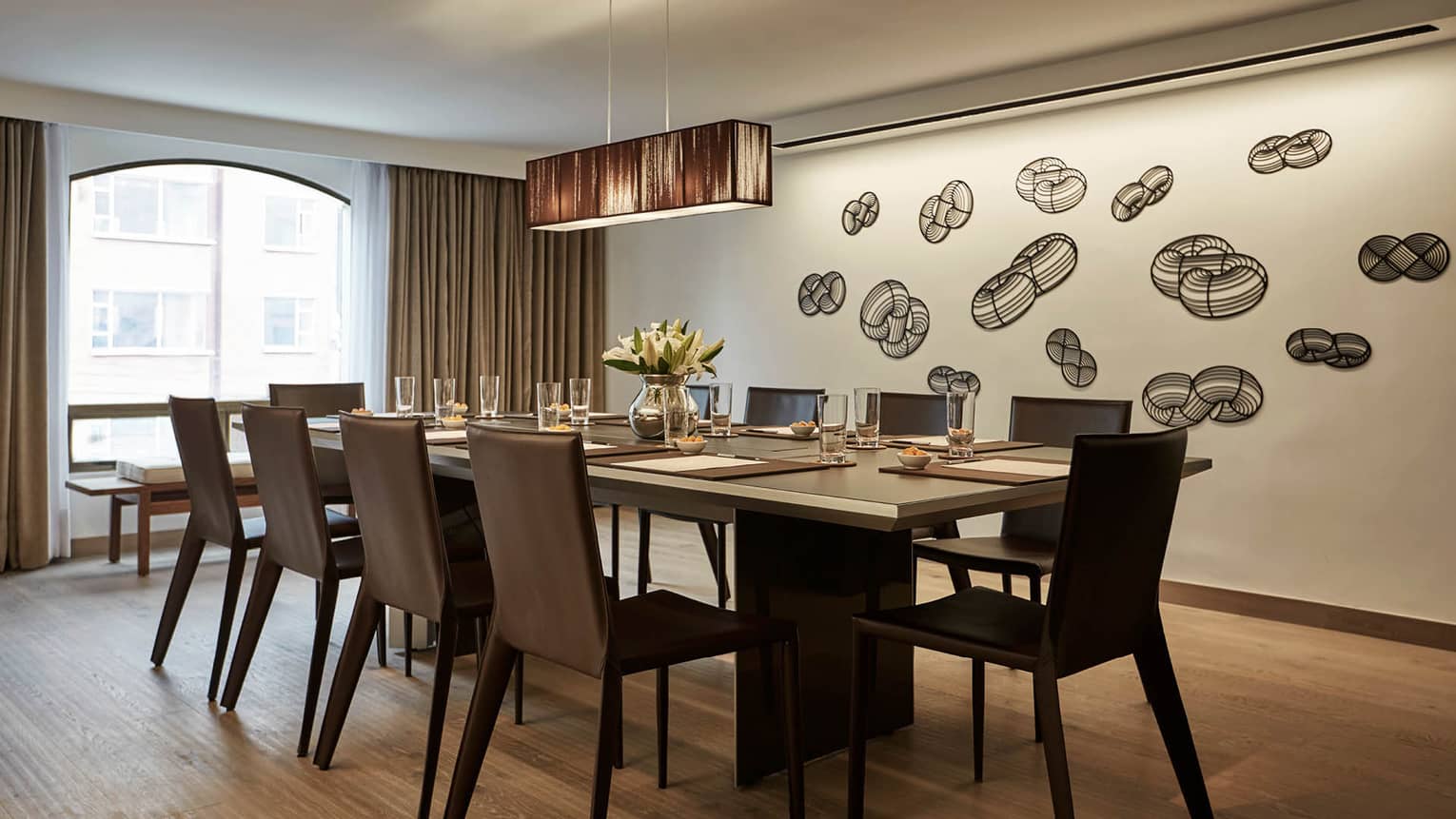 Modern meeting room with table, leather chairs by arched window, accent wall with geometric decals