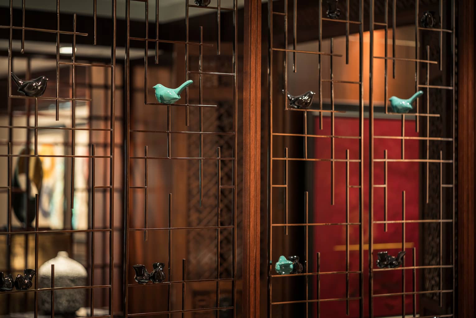 Small, colourful ceramic birds sit on wood screen