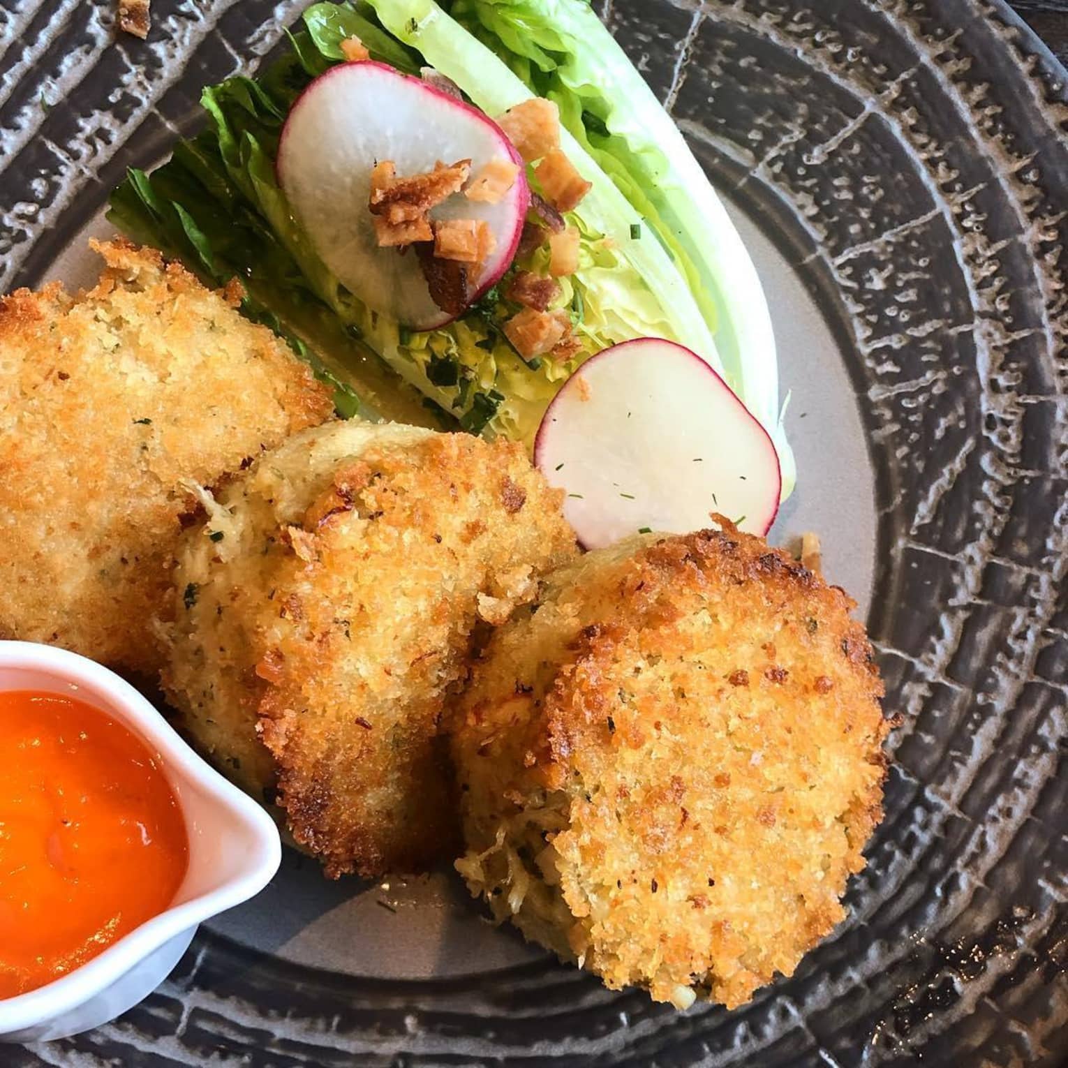 Three fried cakes, lettuce and radish rounds on plate