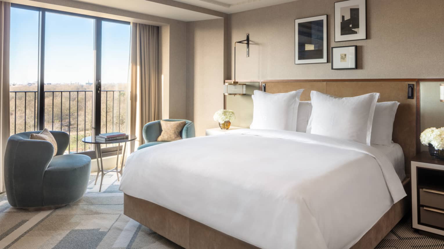 Premier King Room with white linens, blue accent chairs and table, floor-to-ceiling windows with city views