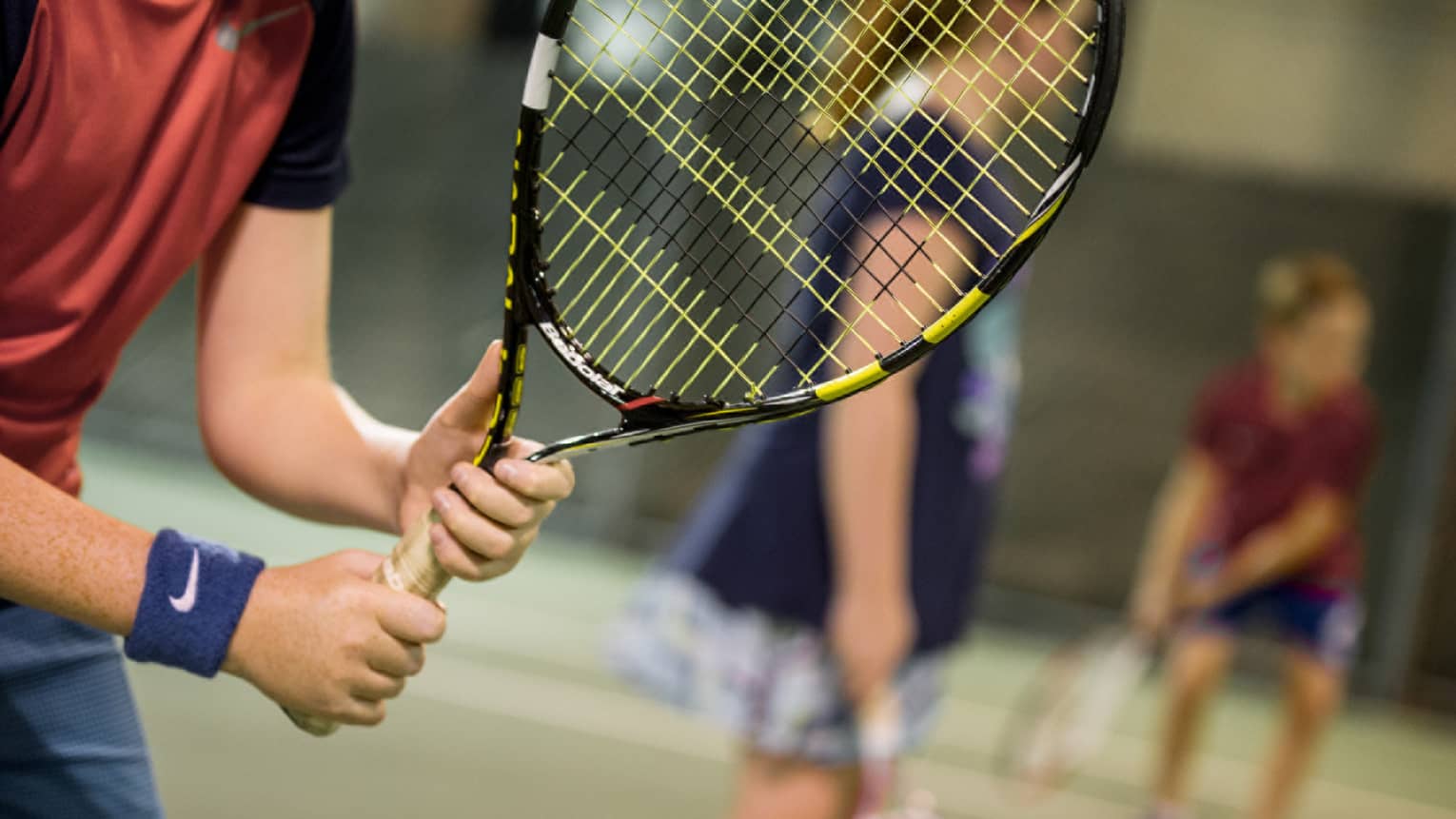 Close-up of hands holding yellow-and-black tennis racket