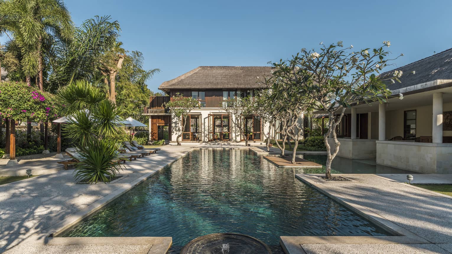 Turquoise water in long outdoor swimming pool leading to Residence 