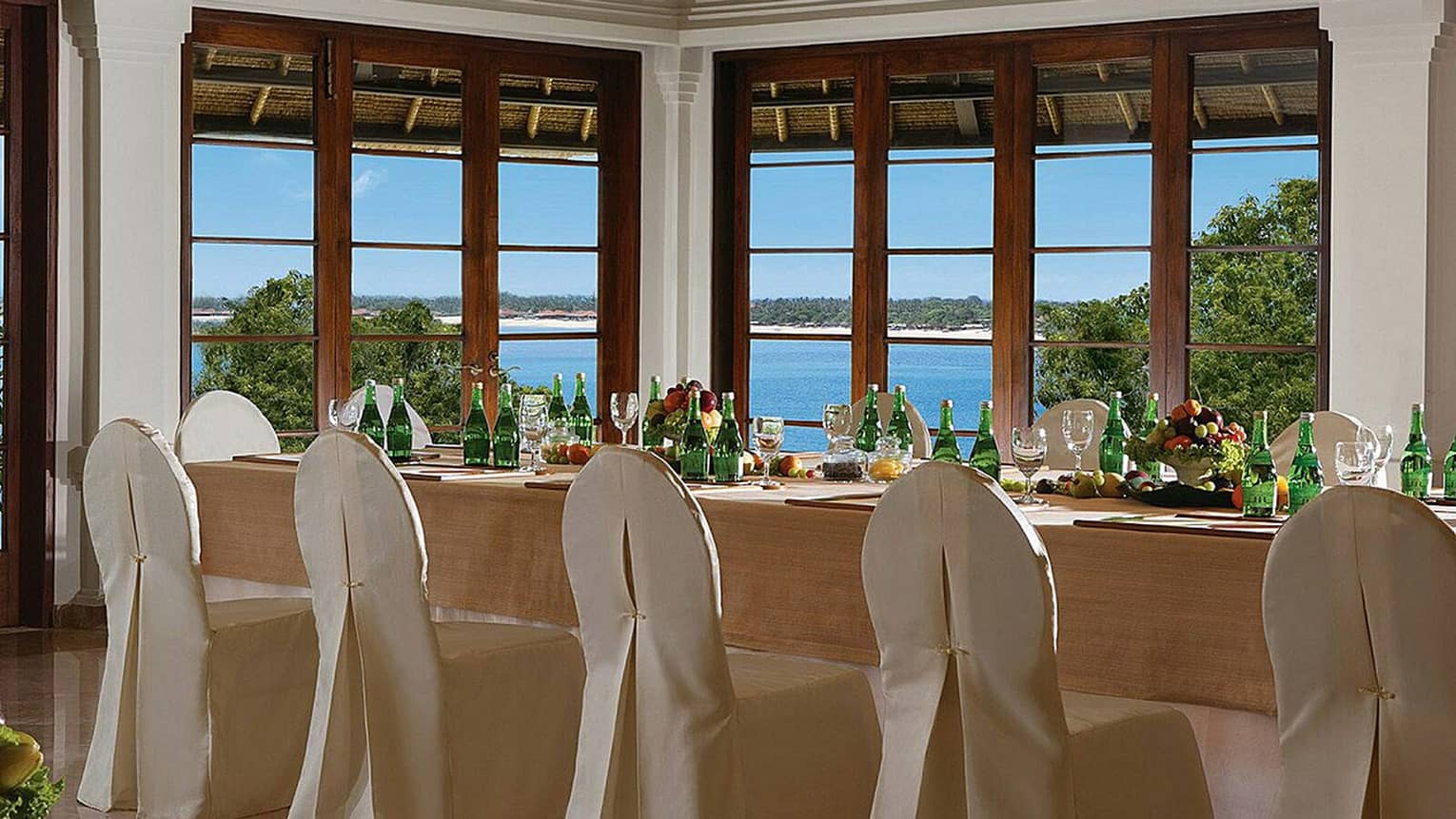 Jepun Sari king banquet table with silk covered chairs by corner windows