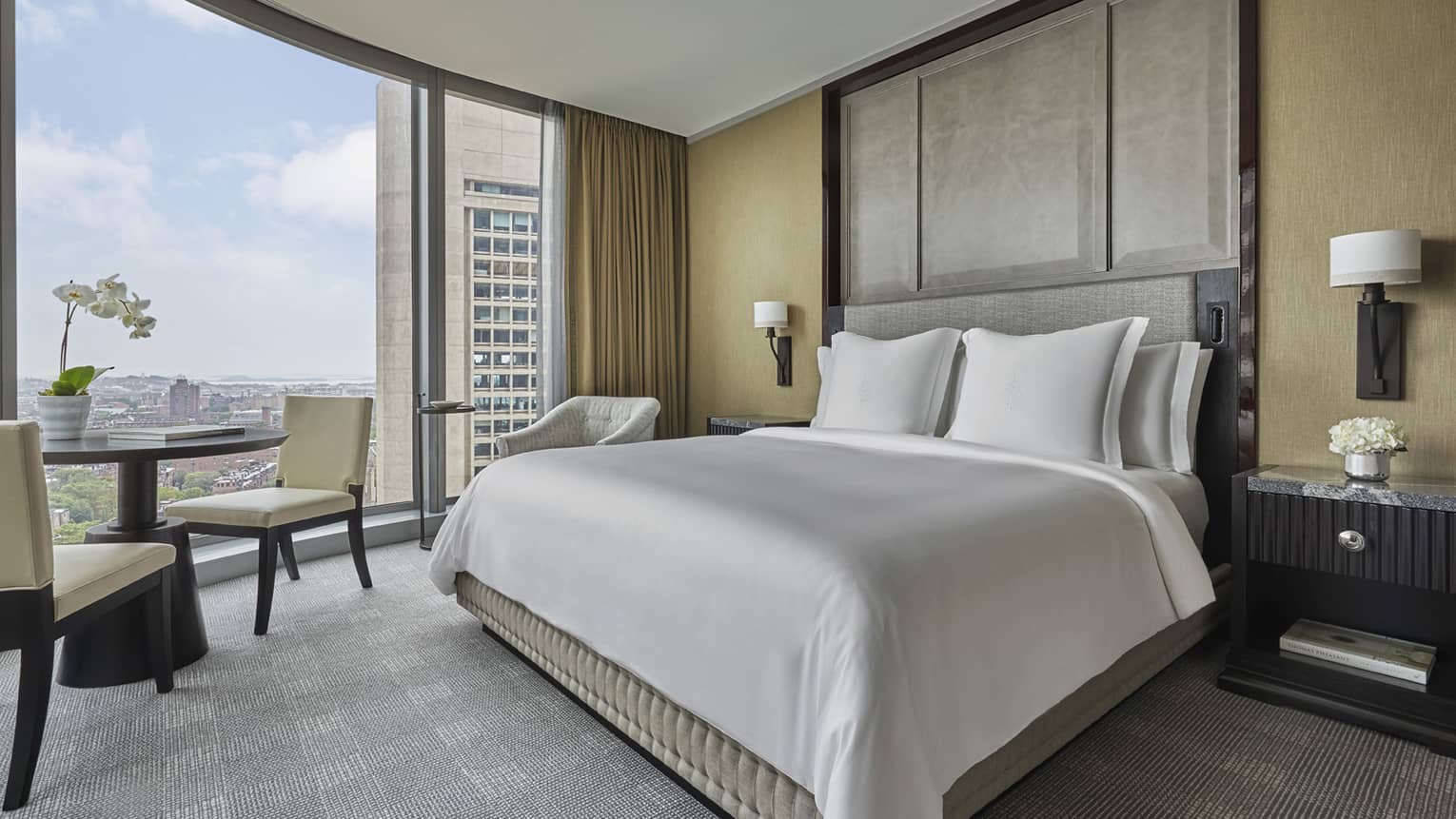 a king bed and small round table in the corner suite at four seasons hotel boston one dalton