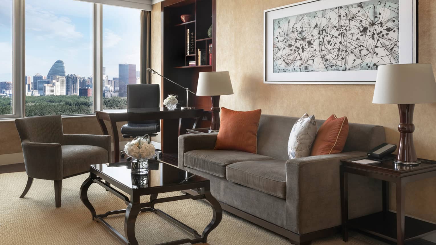 Living room with dark grey, two-seat sofa, chair, desk and chair, and window