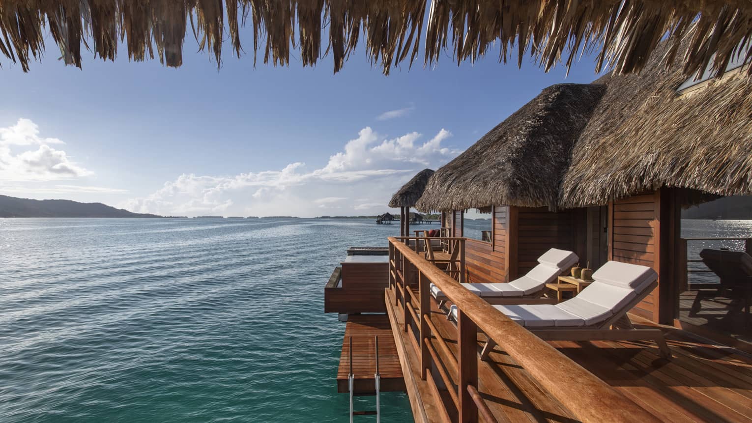 Private deck of Bungalow, with two white sun chairs and water views