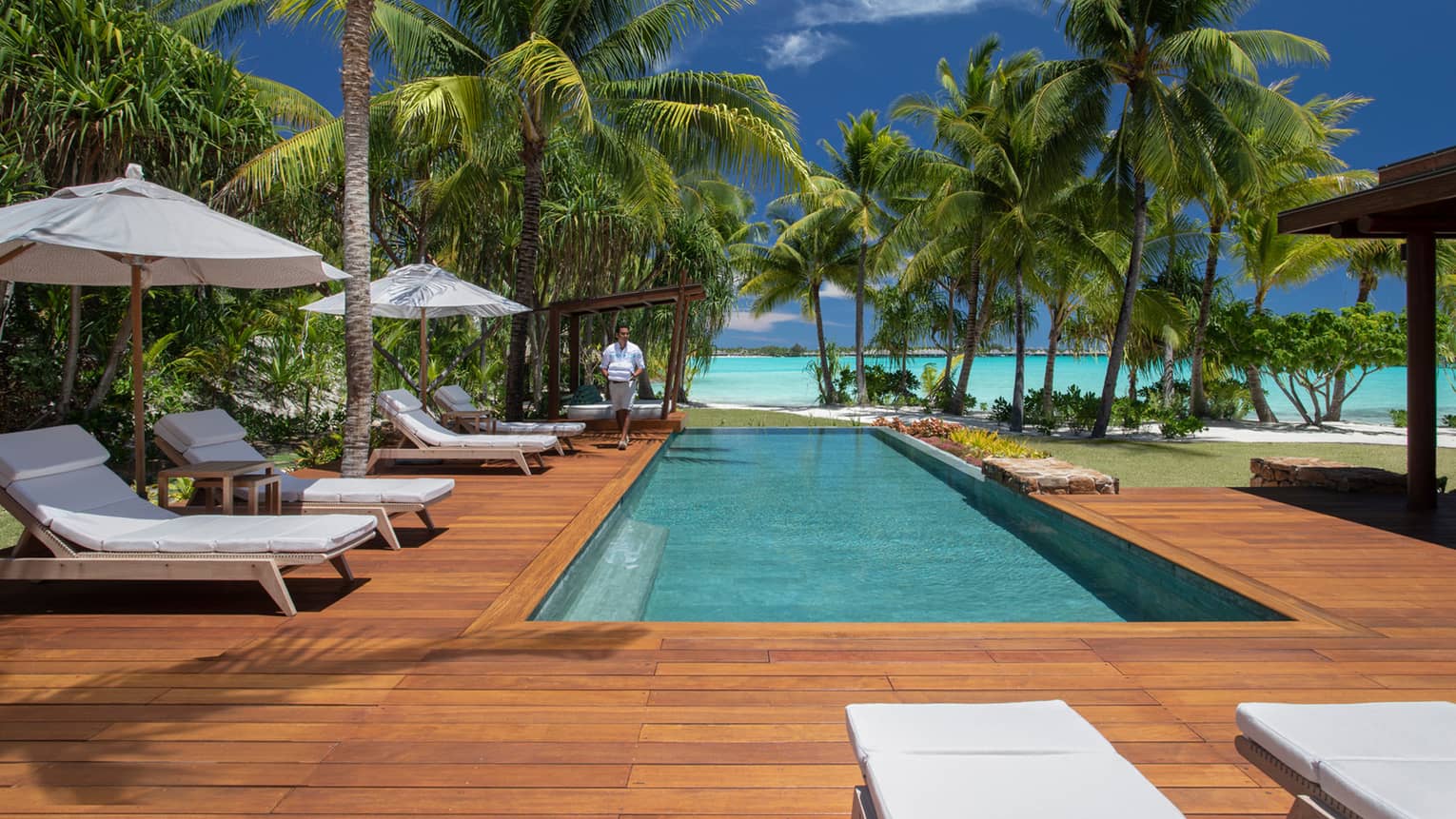 Villa's private pool with a lagoon view, surrounded by a wooden deck with sun chairs