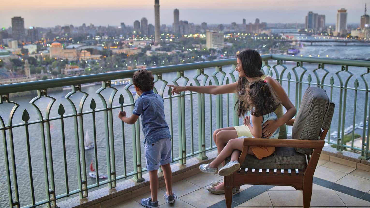 Woman seated with a young girl and beside a young boy standing, overlooking the Nile River and Cairo