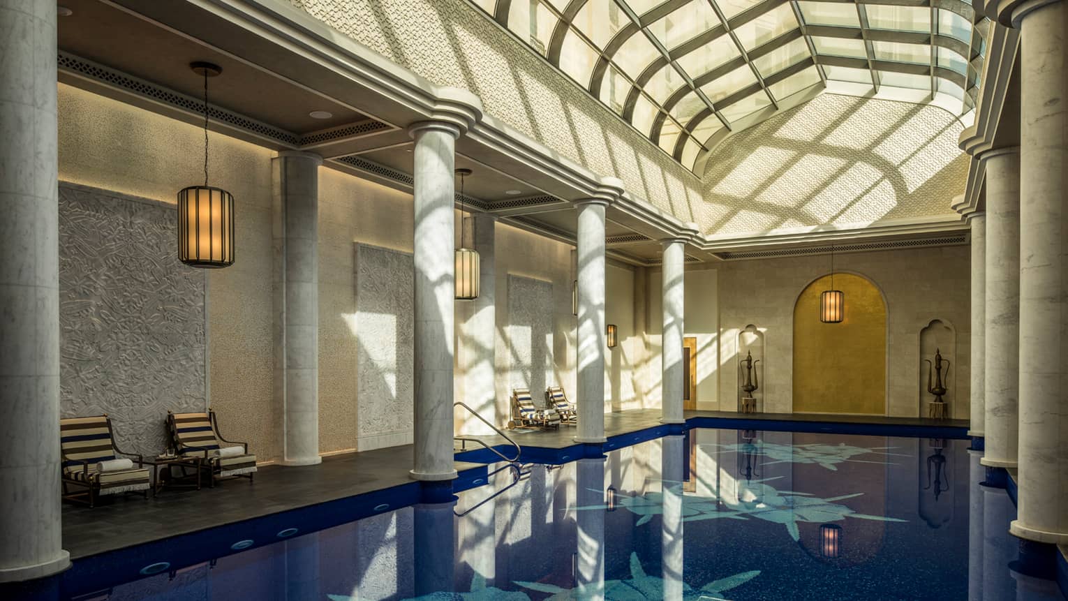 Long indoor swimming pool under curved skylights and tall white pillar columns