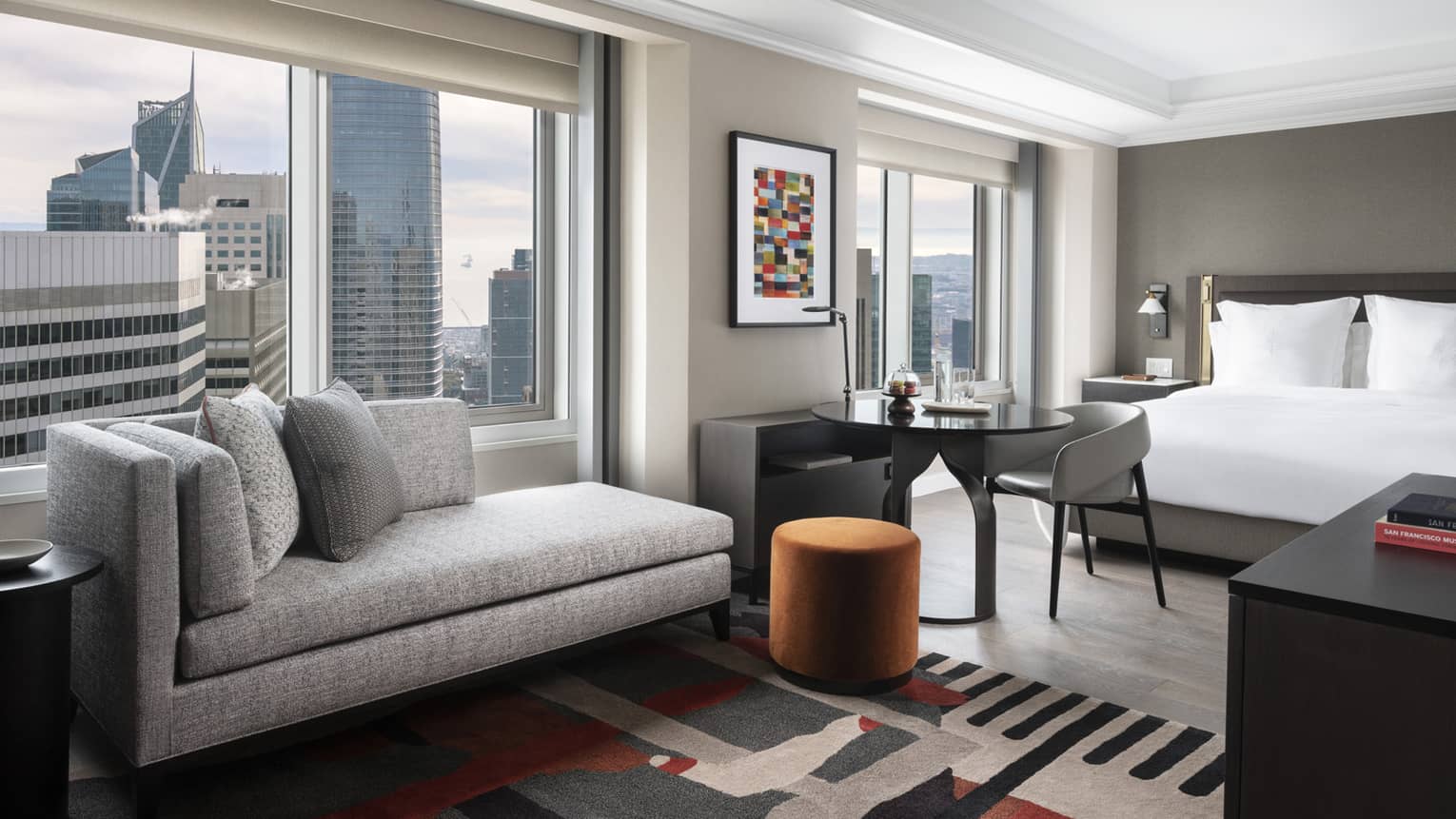 Chaise and small dining table facing panoramic window in suite