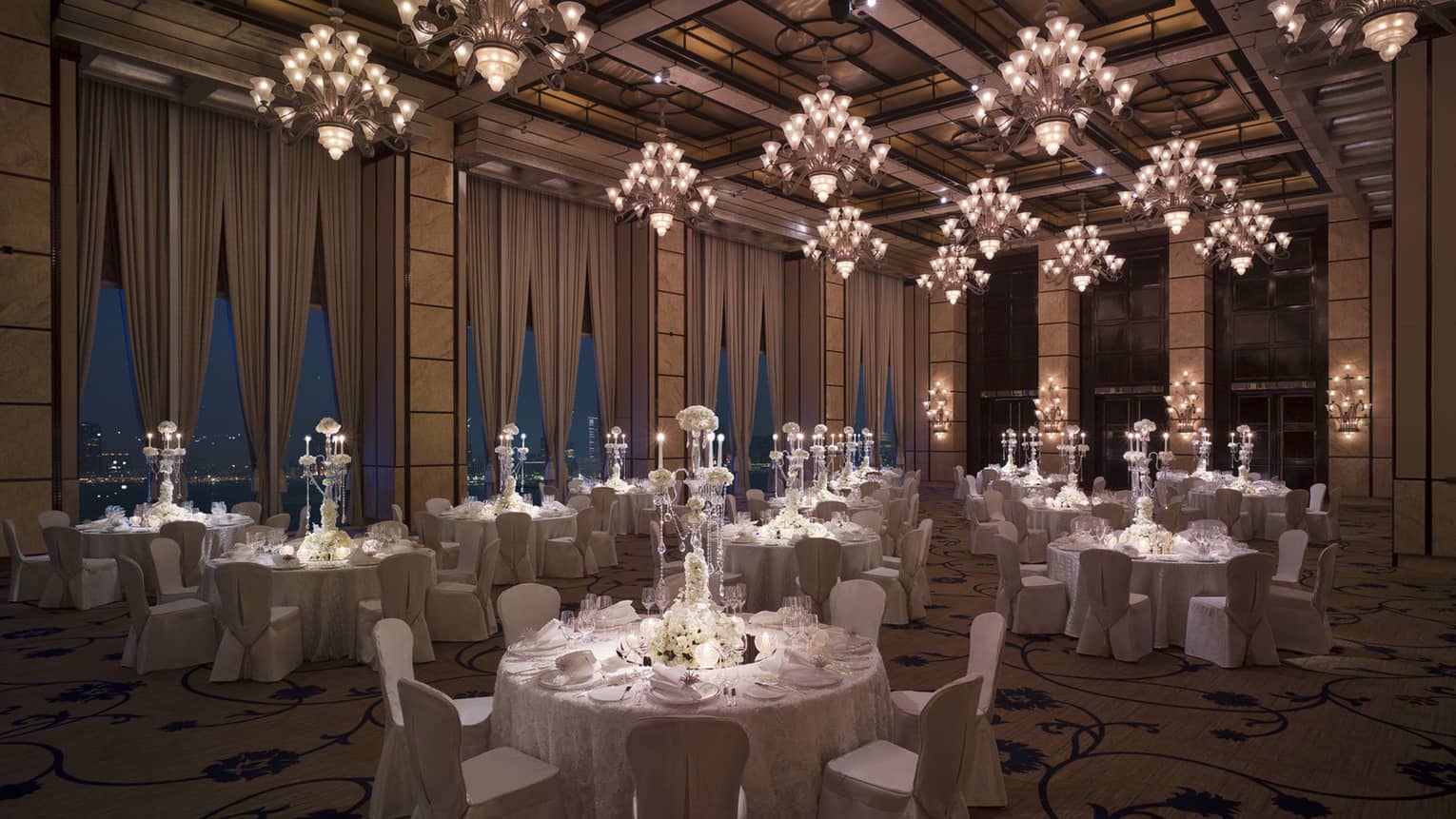 Wedding reception room with round banquet dining tables under small crystal chandeliers