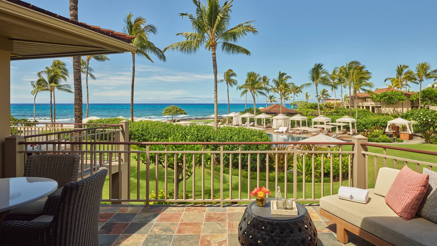 View of the ocean and tropical landscape from a terrace with sofa, dining table