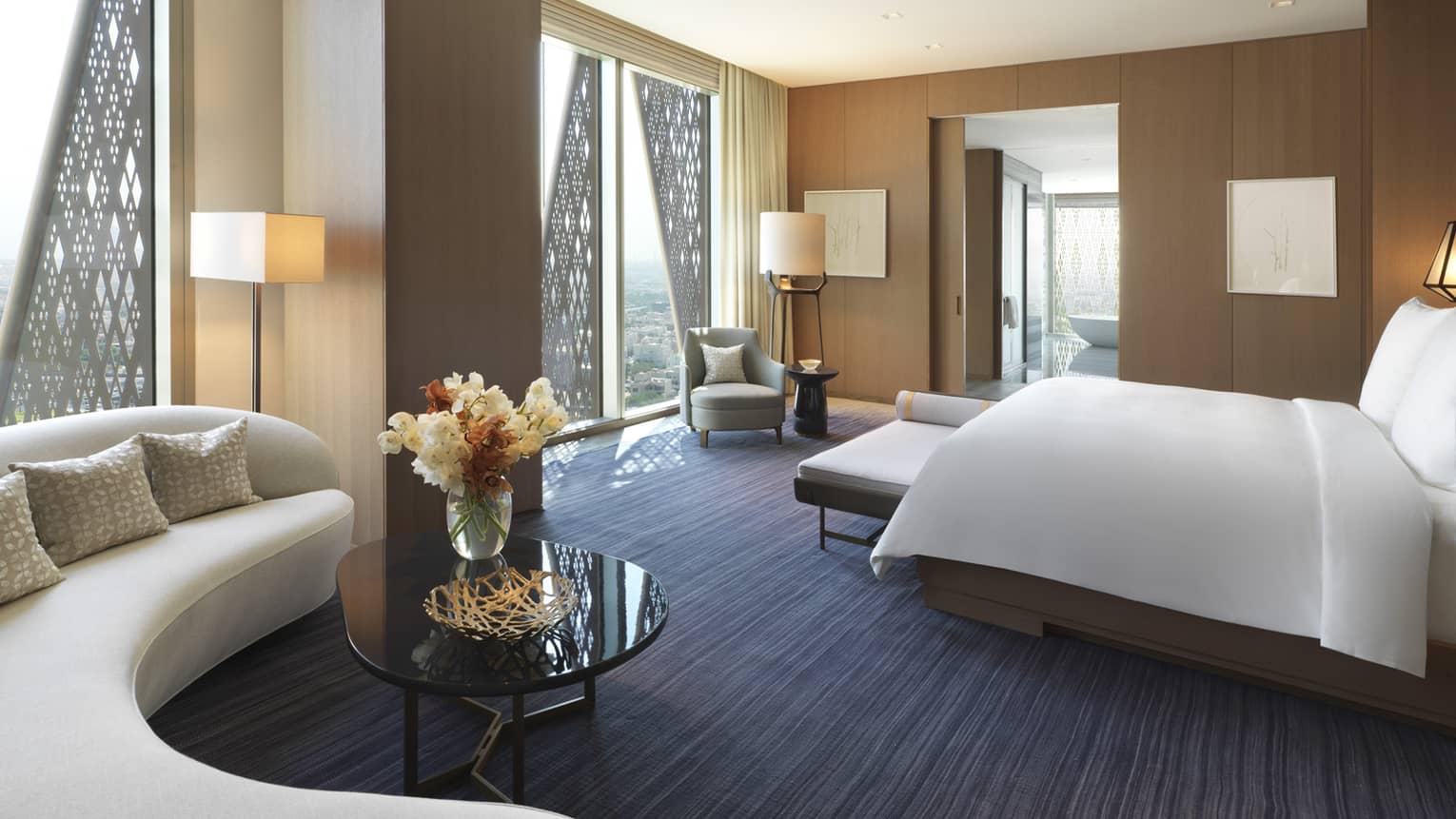 State Suite curved white sofa, coffee table with fresh flowers, bed, armchair by window