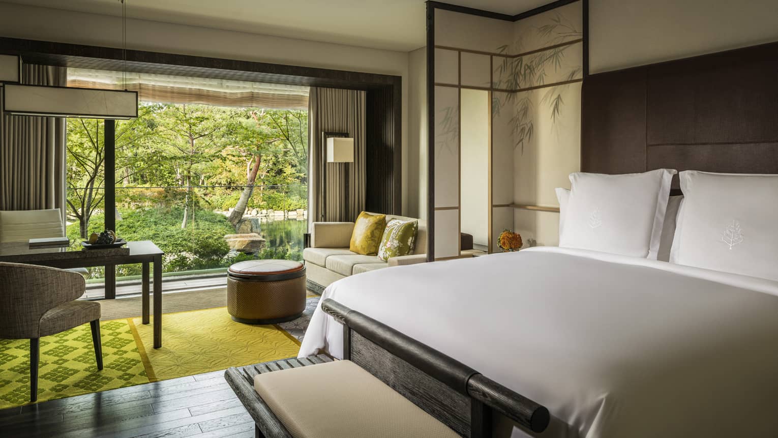 Premier Room bed, desk, sofa and round ottoman by patio door, garden views