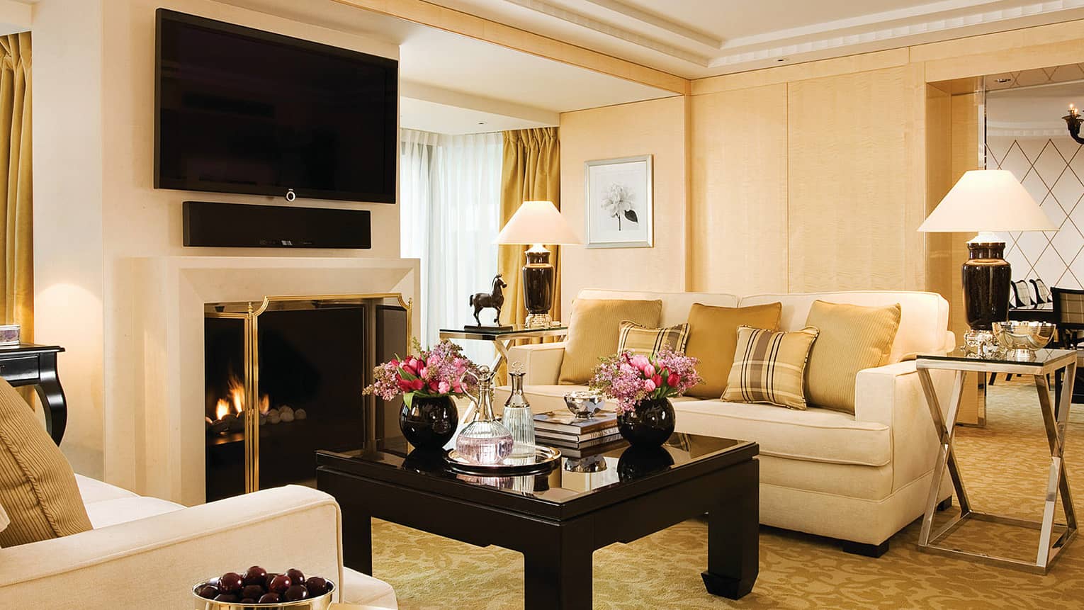 Garden Suite white sofas with gold plaid pillows, flowers, bowl of chocolates on tables, TV