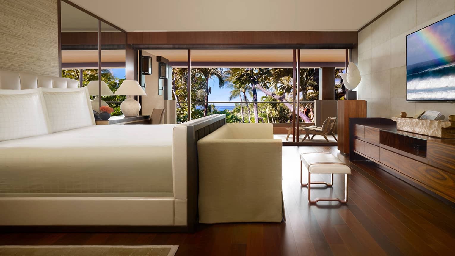 Ohana Partial Ocean-View Suite side view of bed with small white sofa, bench at foot, wood floors