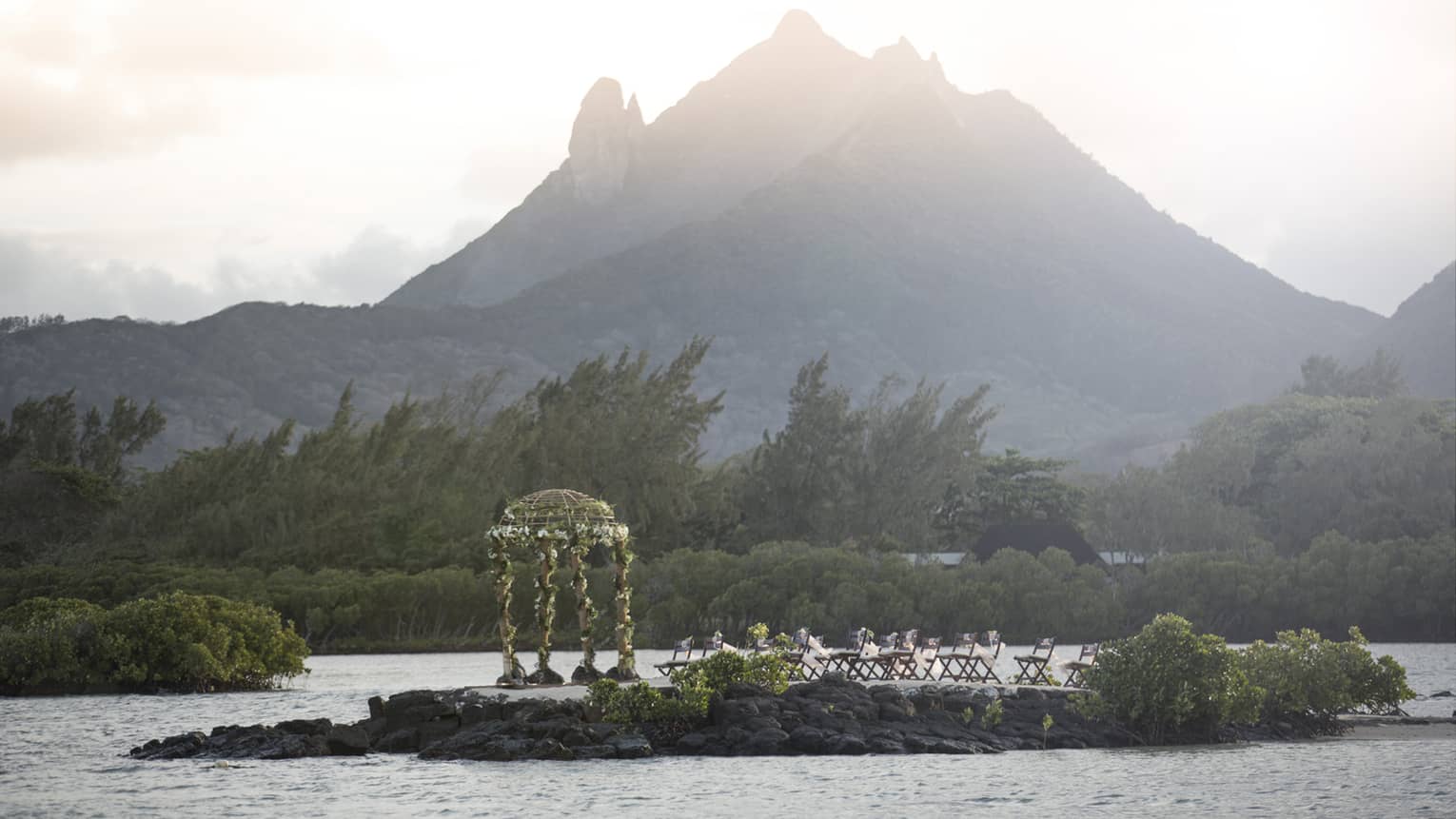 Wedding ceremony on small island in lagoon in front of misty mountain